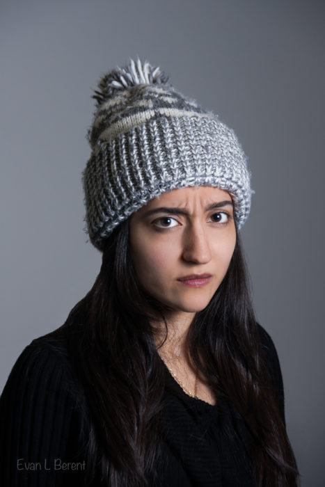 A woman looks sternly into the camera wearing a gray hat