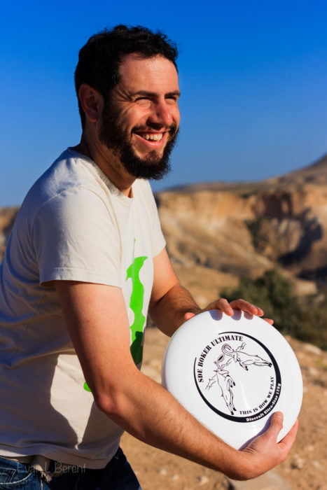 A bearded man poses with a frisbee