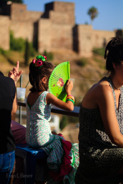 A young girl holds a green fan up in Spain.